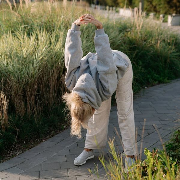 Person stretching gently outdoors, embodying a sense of well-being and flexibility.